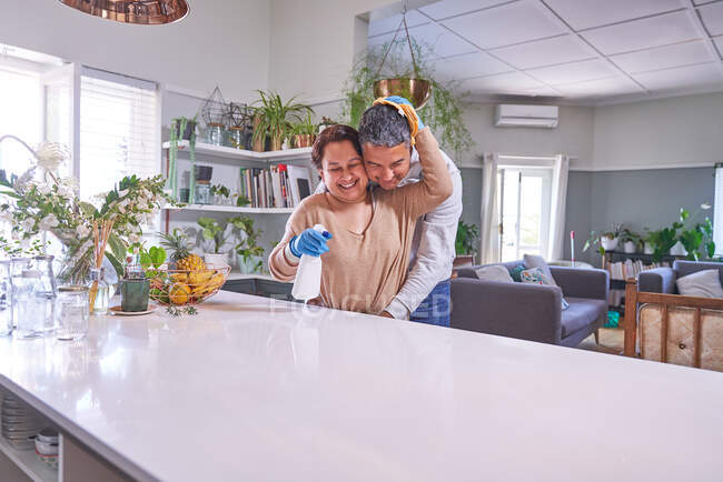 Zärtlich reifes Paar umarmt und putzt Kücheninsel — Stockfoto