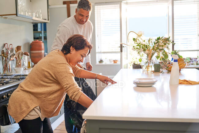 Mature couple cleaning kitchen — Stock Photo