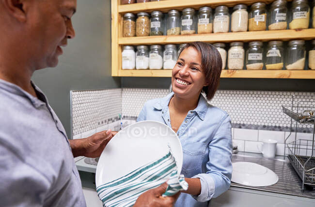 Happy couple drying dishes in kitchen — Stock Photo