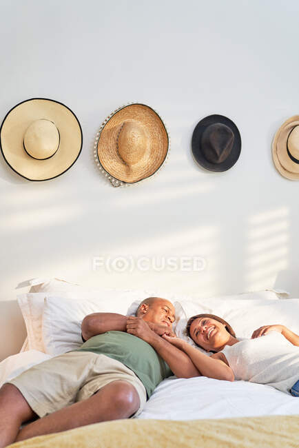 Happy affectionate couple relaxing and talking on bed — Stock Photo