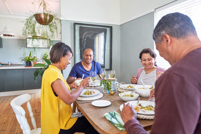 Mature couple friends talking and eating lunch at dining table — Stock Photo
