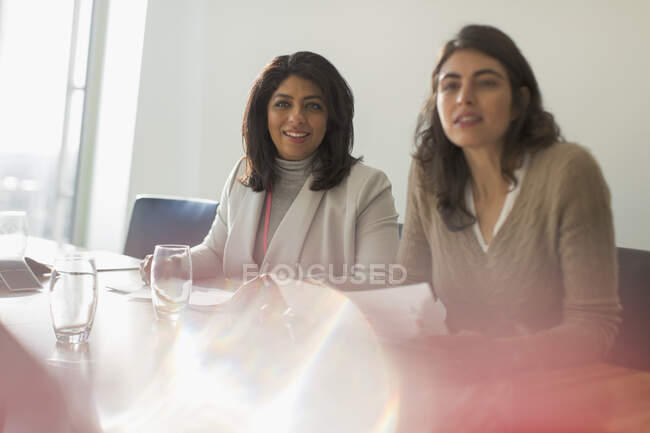 Mujeres de negocios escuchando en la soleada sala de conferencias - foto de stock