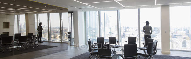 Geschäftsmann steht am Fenster eines modernen Konferenzraums — Stockfoto