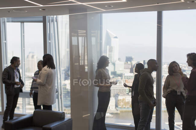 Ділові люди розмовляють у високогірному вікні офісу — стокове фото