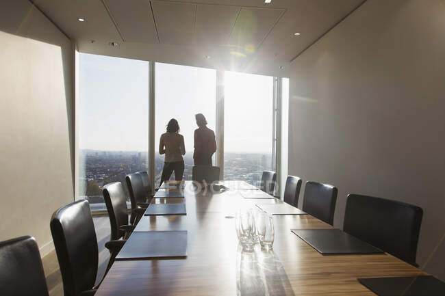 Geschäftsleute unterhalten sich am sonnigen Konferenzzimmerfenster eines Hochhauses — Stockfoto