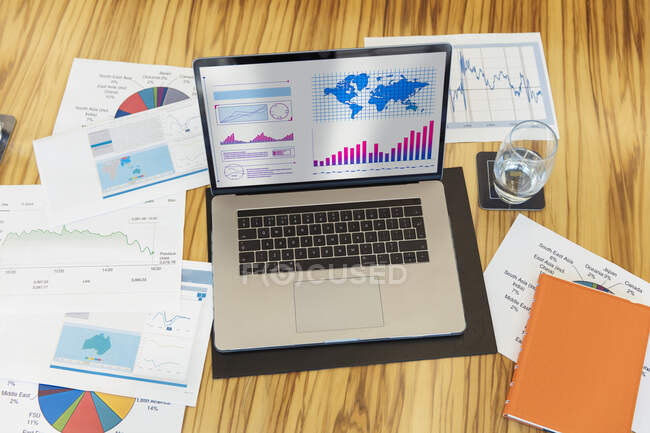 Charts and graphs on laptop and paperwork — Stock Photo
