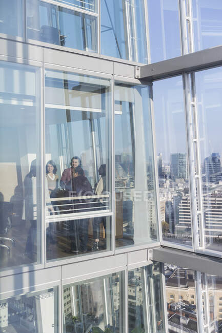 Business people talking at sunny modern highrise office window — Stock Photo