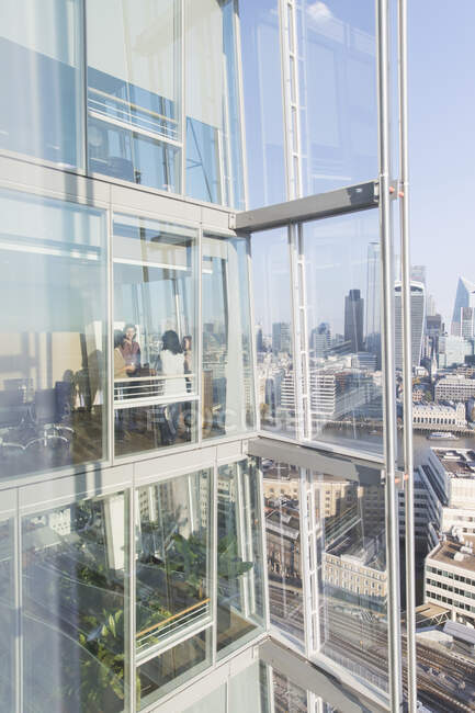 Geschäftsleute unterhalten sich am sonnigen modernen Bürofenster eines Hochhauses — Stockfoto