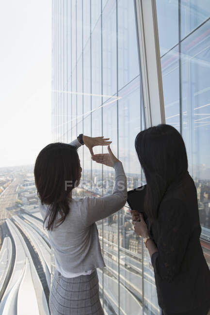 Businesswomen talking at highrise office window — Stock Photo