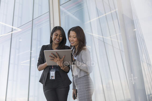 Geschäftsfrauen mit digitalem Tablet sprechen am Bürofenster — Stockfoto