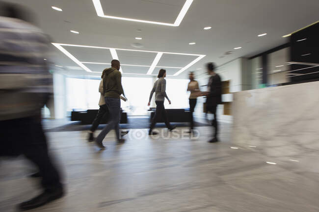 Gente de negocios caminando en el vestíbulo - foto de stock