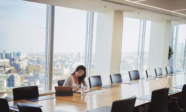 Dedicated businesswoman preparing in sunny urban conference room — Stock Photo