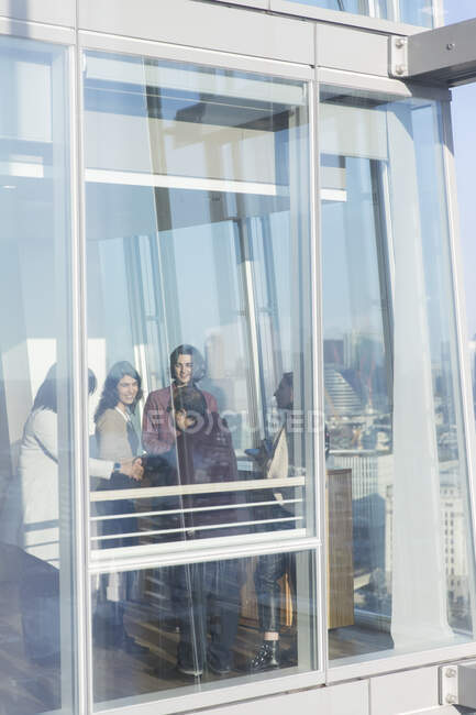 Gente de negocios hablando en la ventana de la oficina soleada - foto de stock