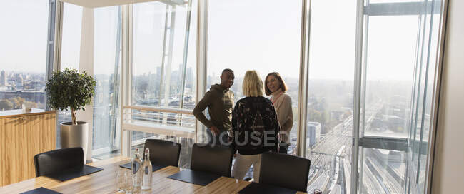 Geschäftsleute unterhalten sich am sonnigen Bürofenster eines Hochhauses — Stockfoto