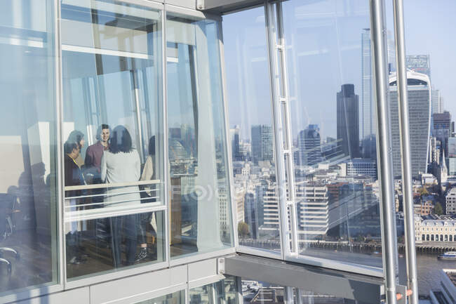Geschäftsleute unterhalten sich am sonnigen Bürofenster eines städtischen Hochhauses — Stockfoto