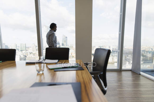 Nachdenklicher Geschäftsmann betrachtet Stadtbild am Fenster eines Konferenzraums — Stockfoto