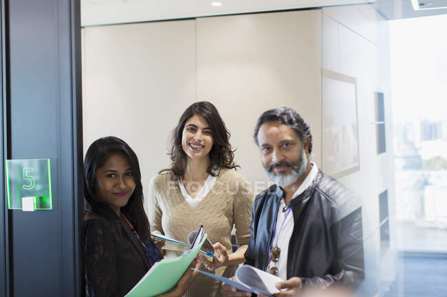 Retrato confiante empresários com papelada no escritório — Fotografia de Stock