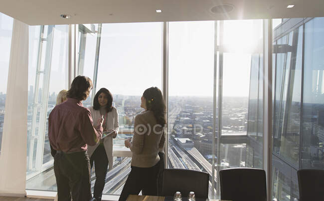 Pessoas de negócios conversando na janela do escritório ensolarado highrise — Fotografia de Stock