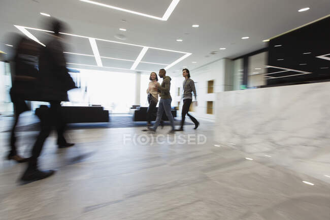 Деловые люди, идущие в офисном холле — стоковое фото