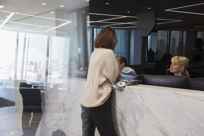 Бізнес-леді розмовляє з рецептором в офісному вестибюлі — стокове фото