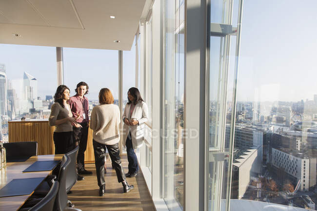 Pessoas de negócios conversando na janela do escritório ensolarado highrise — Fotografia de Stock