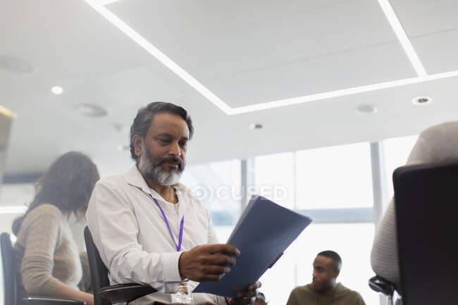 Konzentrierter Geschäftsmann liest Papierkram in Besprechung — Stockfoto