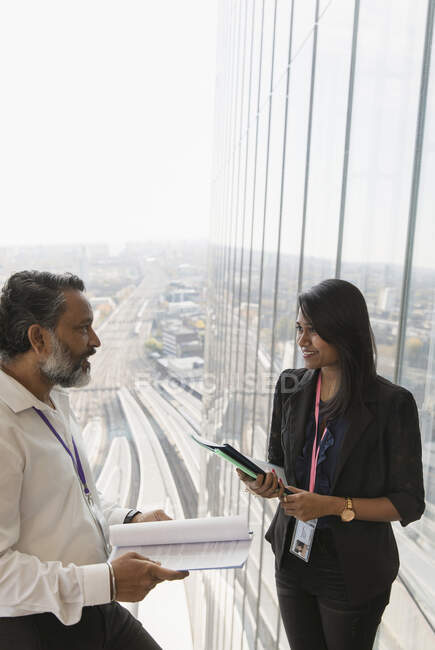 Gente de negocios discutiendo papeleo en ventana de oficina de rascacielos - foto de stock