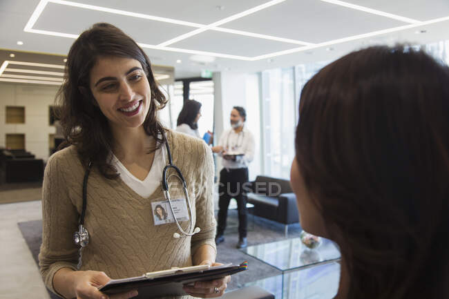Усміхнена жінка-лікар розмовляє з колегою в офісі — стокове фото