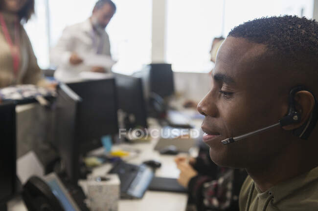 Empresário com fone de ouvido trabalhando no escritório — Fotografia de Stock