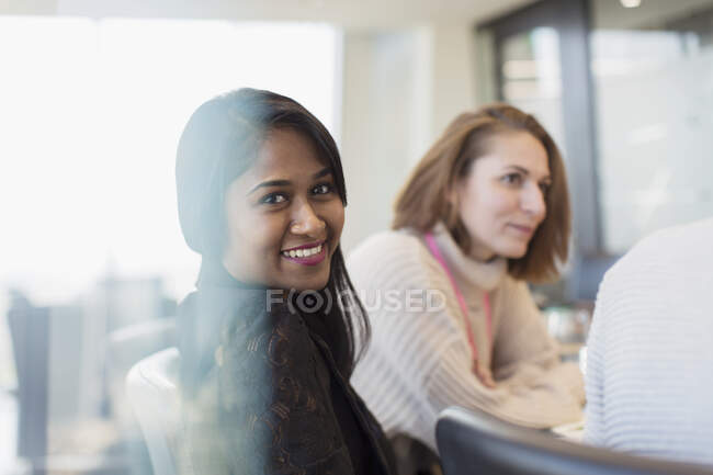 Retrato confiado sonriente mujer de negocios en la reunión - foto de stock