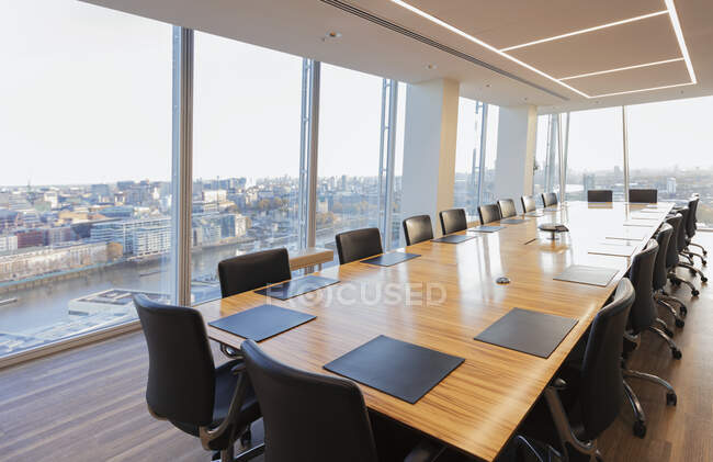 Длинный конференц-стол в современном высотном офисе с видом на город — стоковое фото