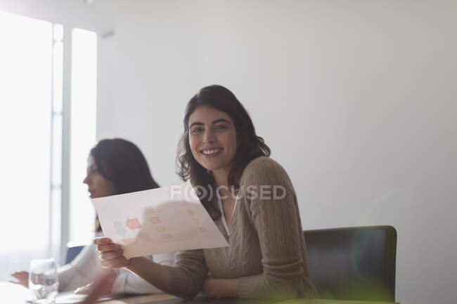 Retrato confiado feliz mujer de negocios con papeleo en la oficina - foto de stock