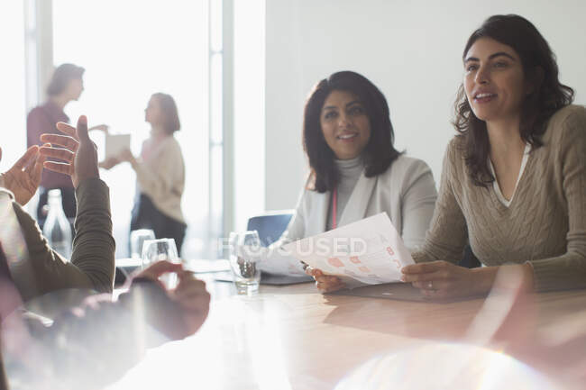 Mulheres de negócios ouvindo na sala de reuniões ensolarada — Fotografia de Stock