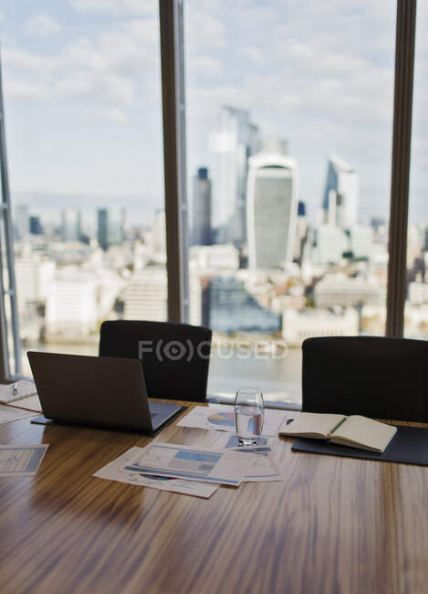 Laptop e papelada na mesa da sala de conferências com vista da cidade — Fotografia de Stock