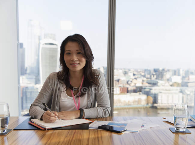 Portrait confident businesswoman planning in highrise conference room — Stock Photo