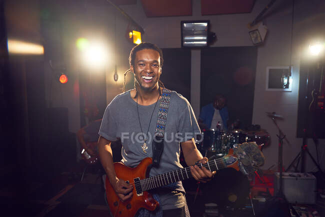 Portrait confident male musician playing guitar in recording studio — Stock Photo