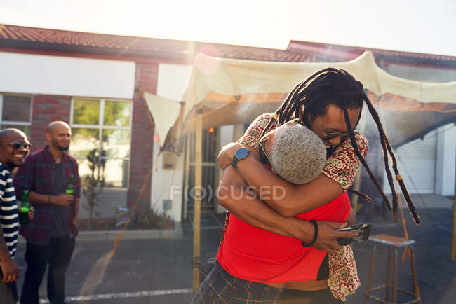 Amigos felices abrazando en soleado estacionamiento. - foto de stock