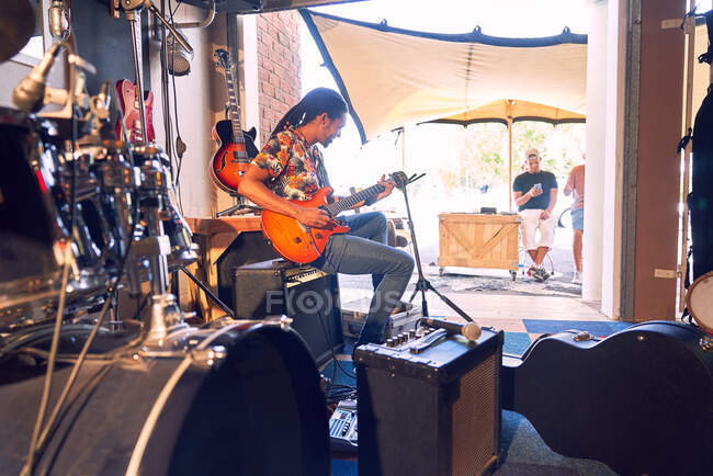 Мужчина-музыкант практикует электрогитару в гаражной студии звукозаписи — стоковое фото