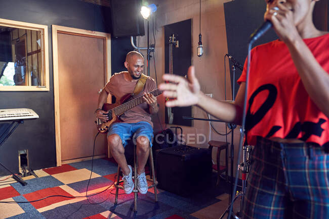 Músicos cantando y tocando guitarra en estudio de grabación - foto de stock