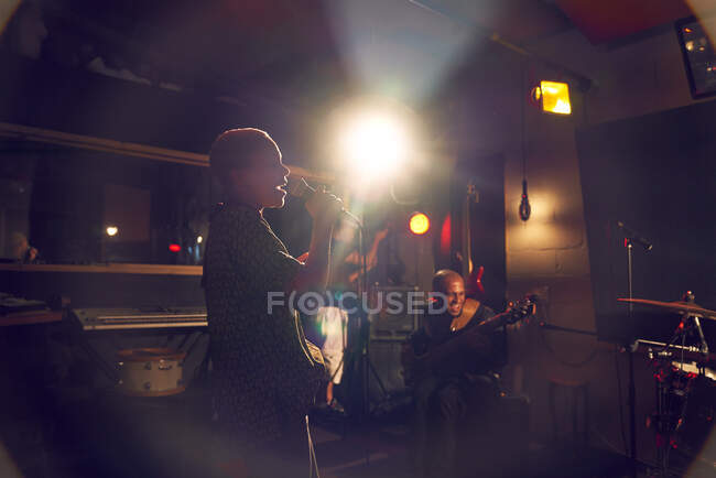 Musicienne chantant au microphone dans un studio d'enregistrement — Photo de stock