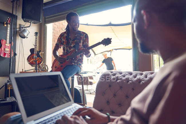 Musiciens avec ordinateur portable et guitare électrique en studio d'enregistrement — Photo de stock