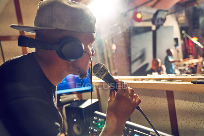 Produttore maschile con microfono che lavora in studio di registrazione musicale — Foto stock