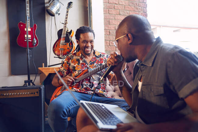 Happy male musicians practicing in recording studio — Stock Photo
