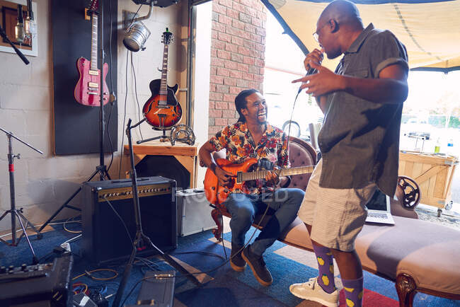 Heureux musiciens masculins pratiquant dans le garage studio d'enregistrement — Photo de stock