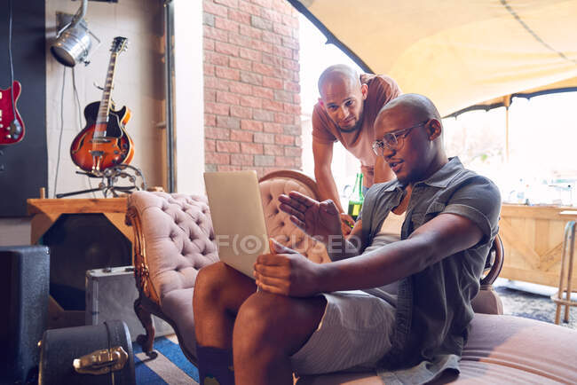 Чоловіки-музиканти з ноутбуком розмовляють в студії запису гаража — стокове фото