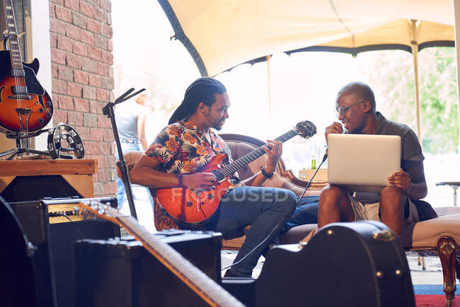 Male musicians with laptop and electric guitar in garage recording studio — Stock Photo