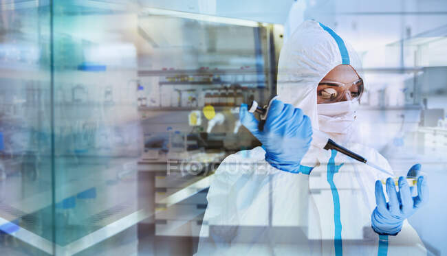 Жінка-вчена в чистому костюмі досліджує коронавірус в лабораторії — стокове фото