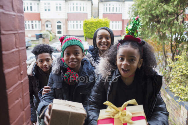 Retrato feliz familia entrega regalos de Navidad en la entrada delantera - foto de stock