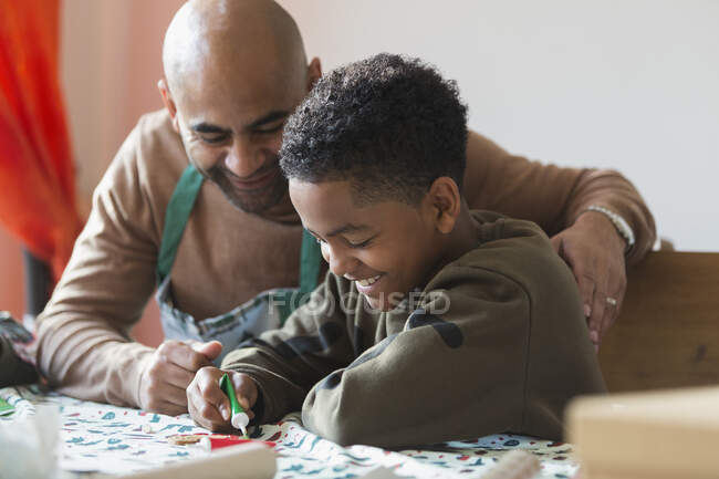 Счастливый отец и сын украшают рождественское печенье — стоковое фото