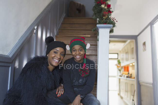 Retrato feliz mãe e filho usando chapéus de Natal na escada — Fotografia de Stock
